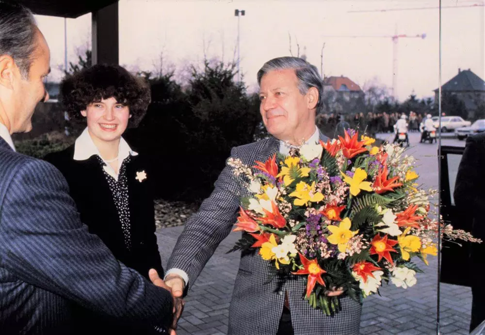 Helmut Schmidt shakes Reinhard Mohn's hand and holds a bouquet of flowers.