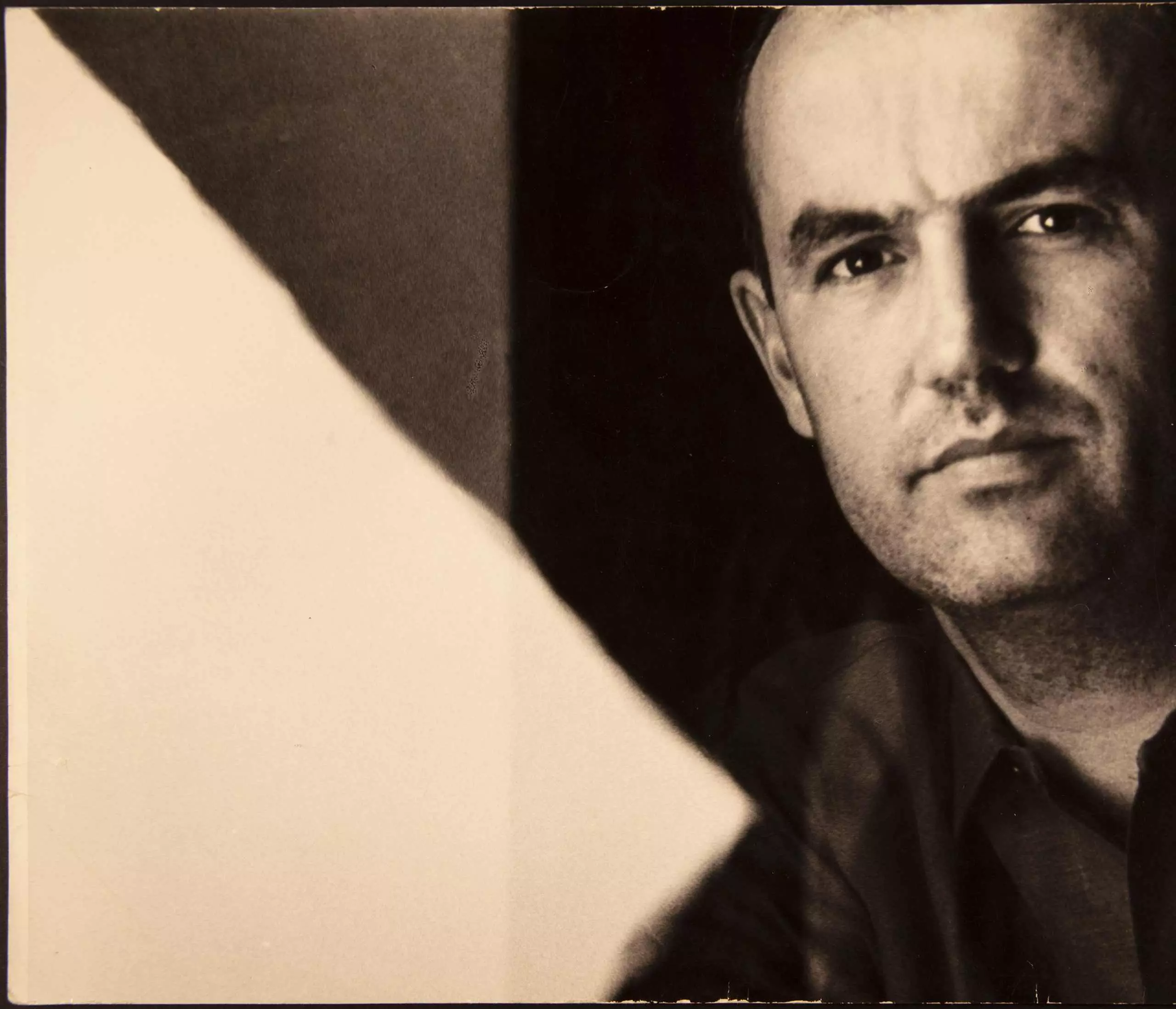 Historisches Porträt eines Mannes, halb im Schatten vor kontrastreichem Hintergrund.