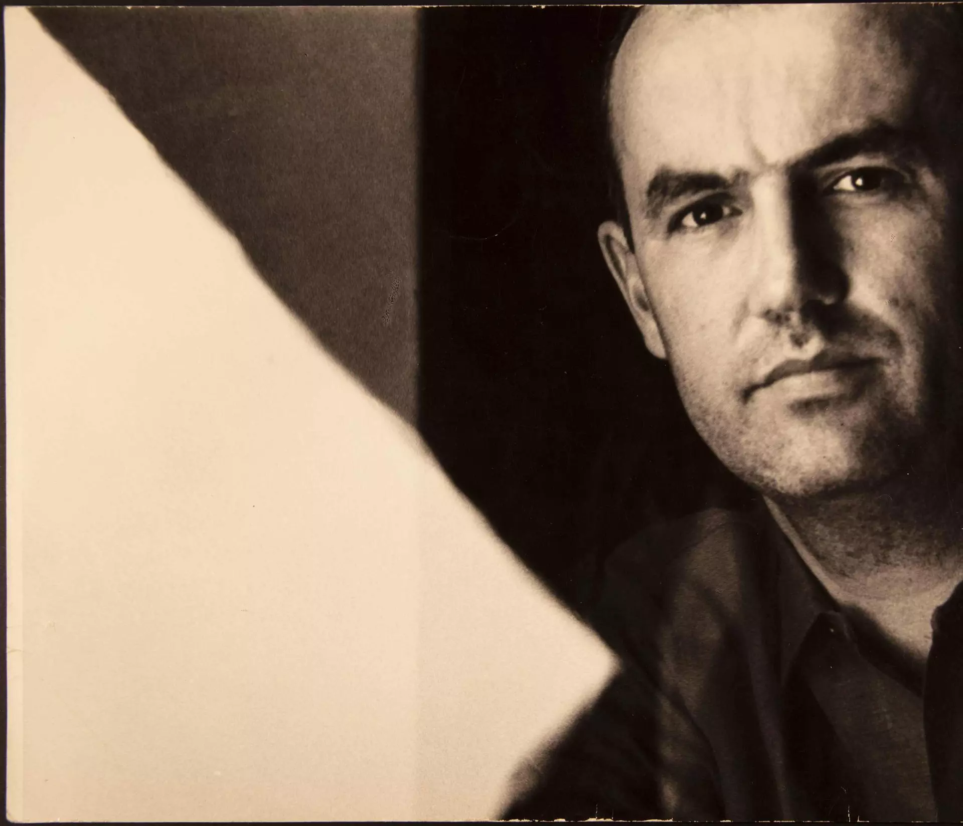 Historisches Porträt eines Mannes, halb im Schatten vor kontrastreichem Hintergrund.