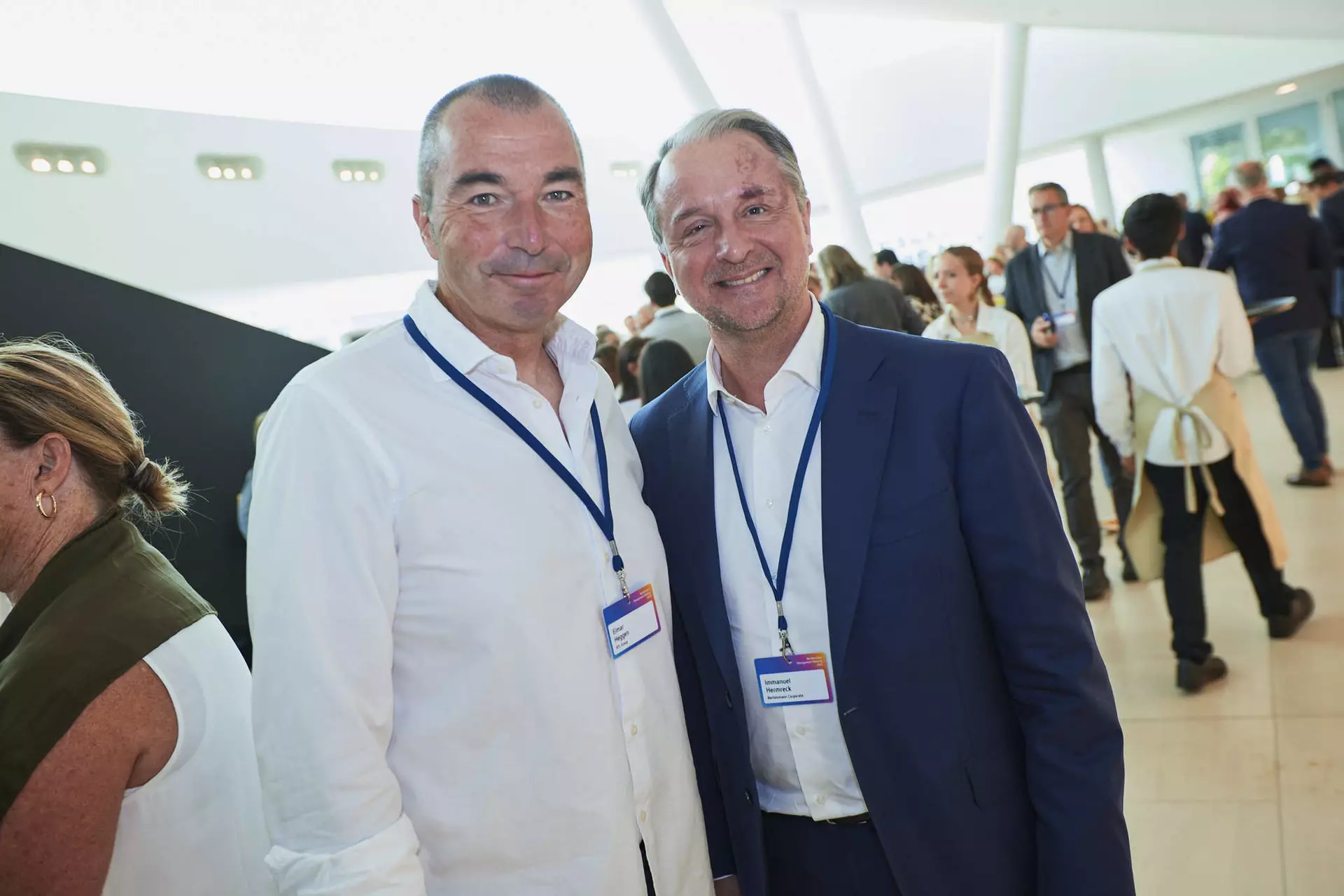Zwei Personen mit Namensschildern stehen lächelnd in hellem Foyer bei Networking-Veranstaltung.