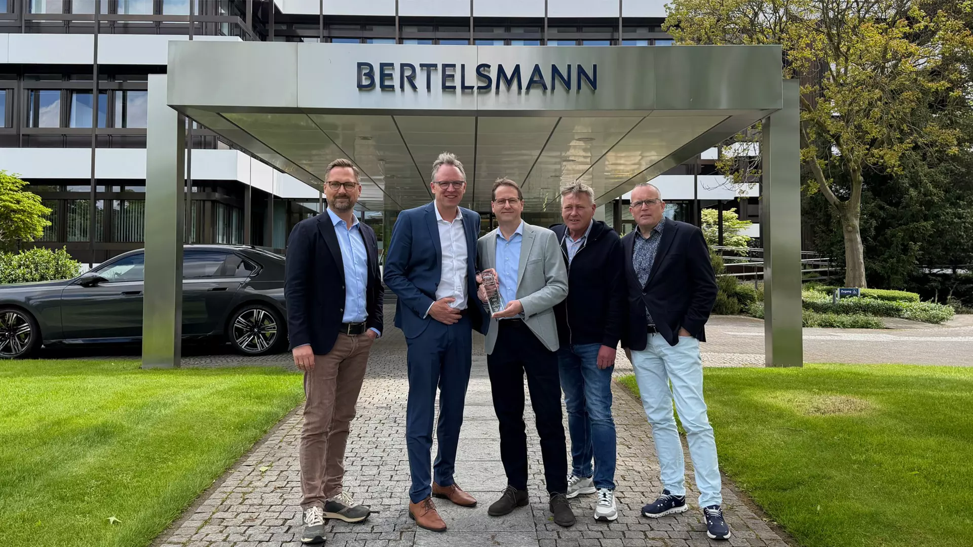 Five men are standing in front of the entrance to the Bertelsmann building