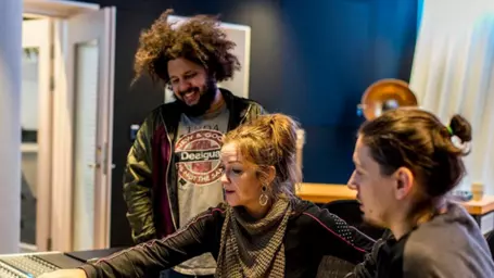 Three people working together in a recording studio.