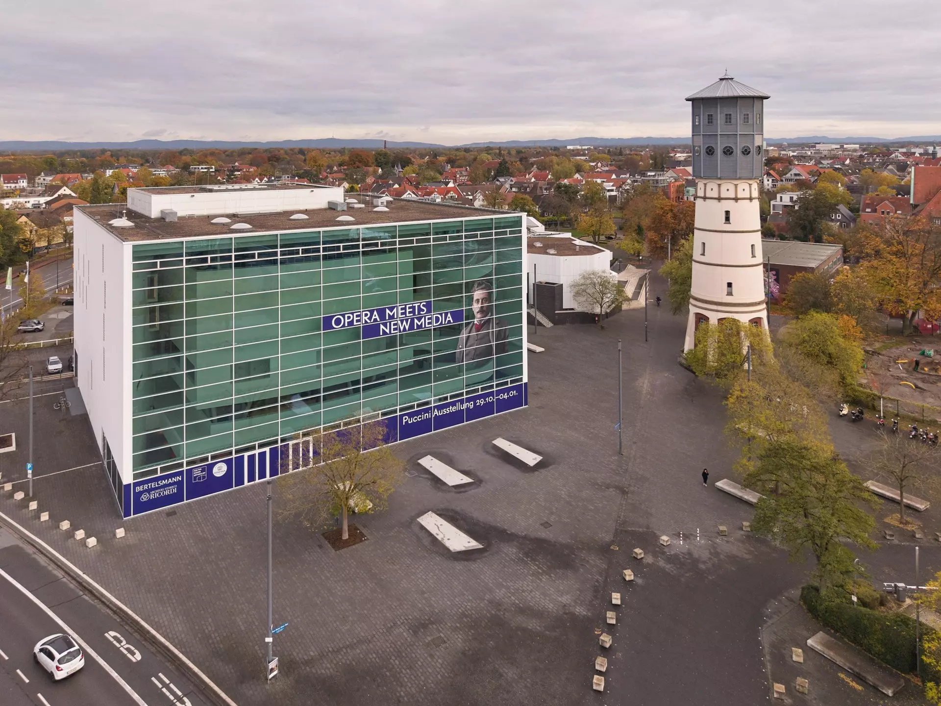 Aerial view of the theater with its exterior facade covered in posters as part of the Puccini exhibition