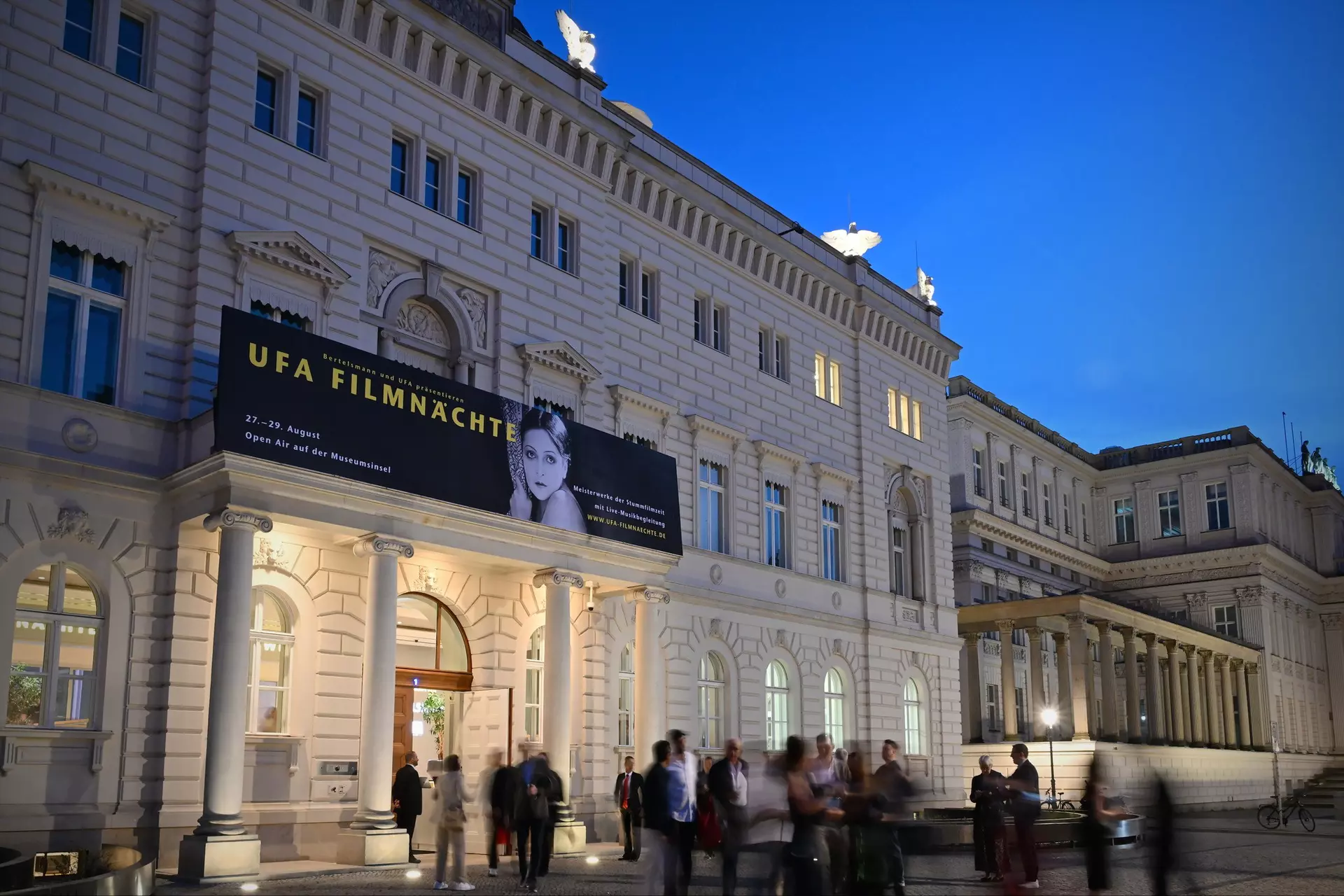 Beleuchteter Eingang der Bertelsmann Repräsentanz Berlin, mit einem Plakat der UFA Filmnächte