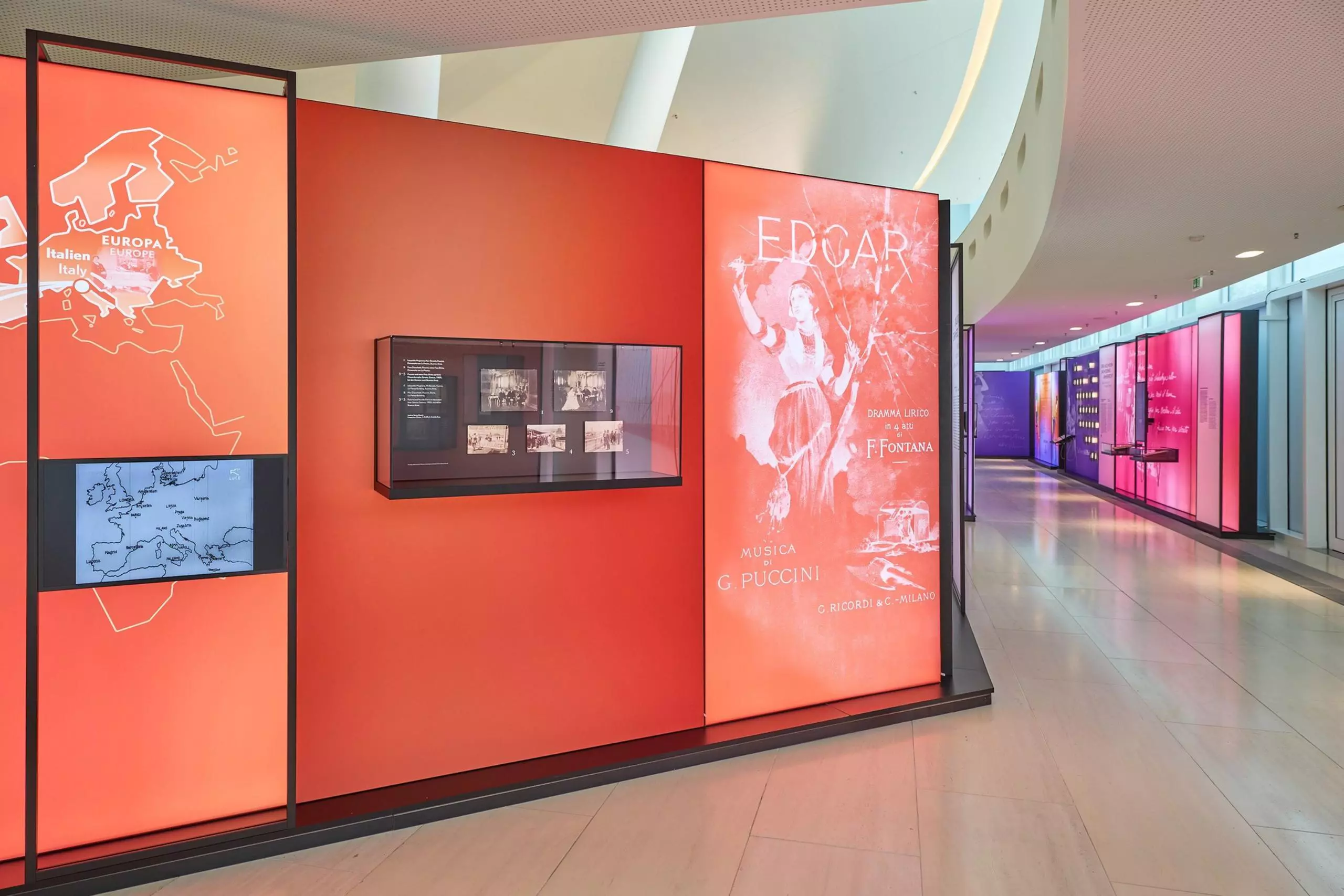 A look at the Puccini exhibition in Gütersloh: numerous exhibits hang in display cases on walls illuminated with colored lights and printed with information