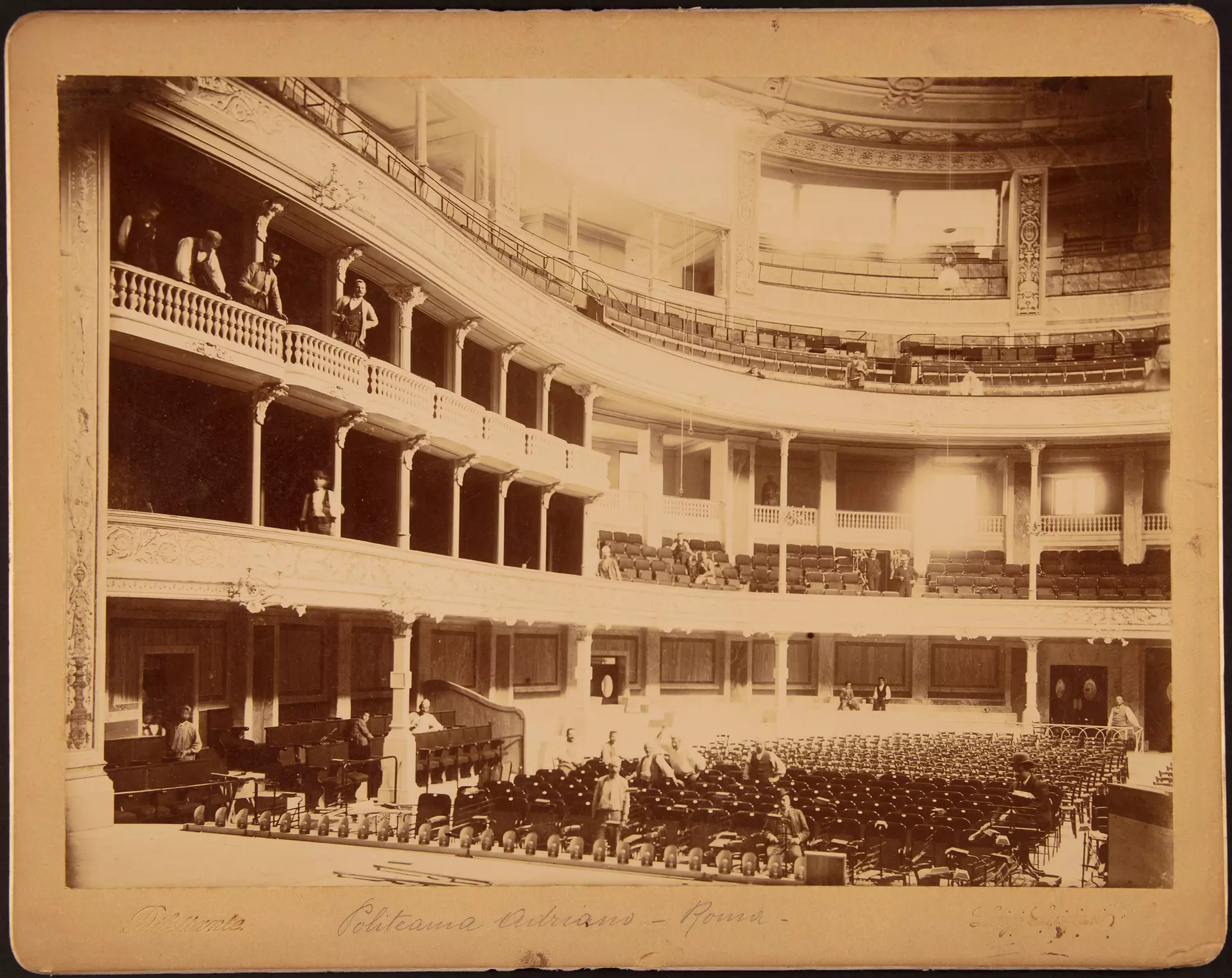 Historische Aufnahme eines Theaterinnenraums mit Rängen, Bühne und Orchester im Parkett.