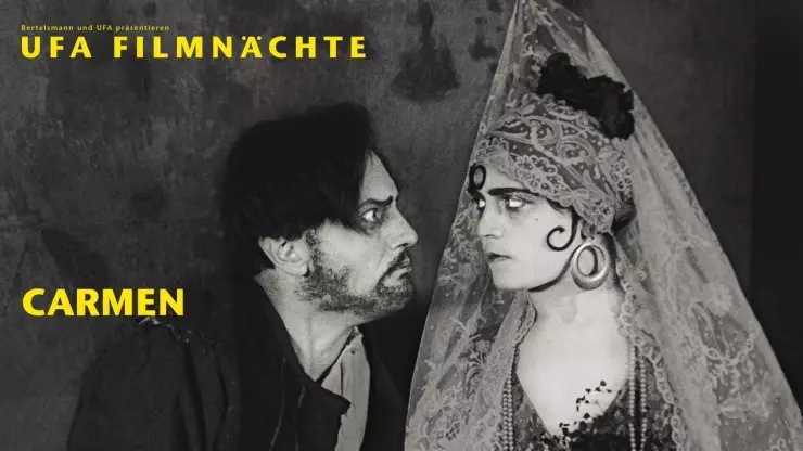 Zwei Figuren aus einem Stummfilm stehen sich dicht gegenüber, dunkelhaariger Mann mit Bart blickt intensiv eine stolze Frau mit Spitzenschleier auf dem Kopf und dunkler Locke auf der Wange  an.