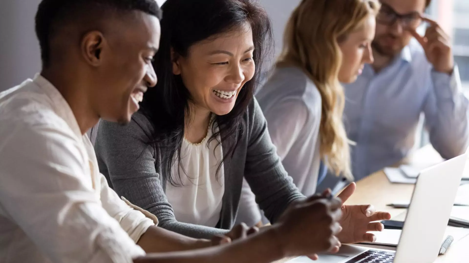 Four people of different skin colors, working in pairs at laptops