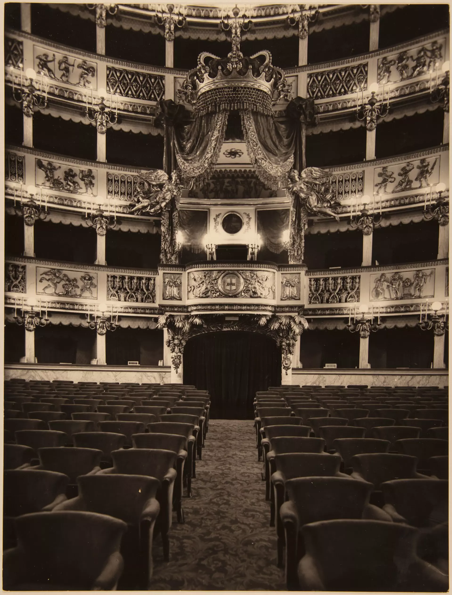 Historische Aufnahme eines prunkvollen Theaterinnenraums mit Rängen, Logen und leeren Sitzreihen.