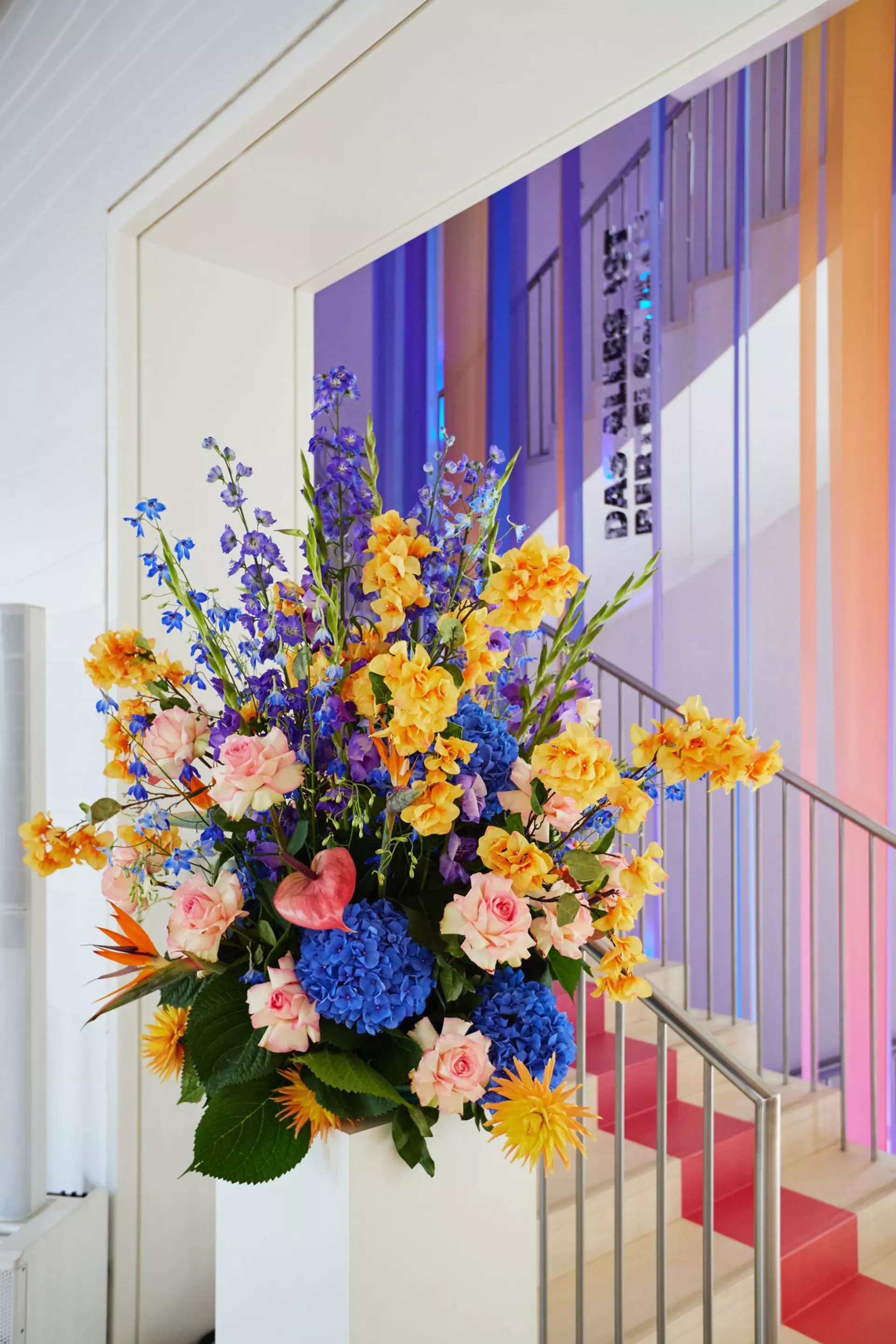 Buntes Blumenbouquet im Foyer der Bertelsmann Repräsentanz vor einem Treppenaufgang.