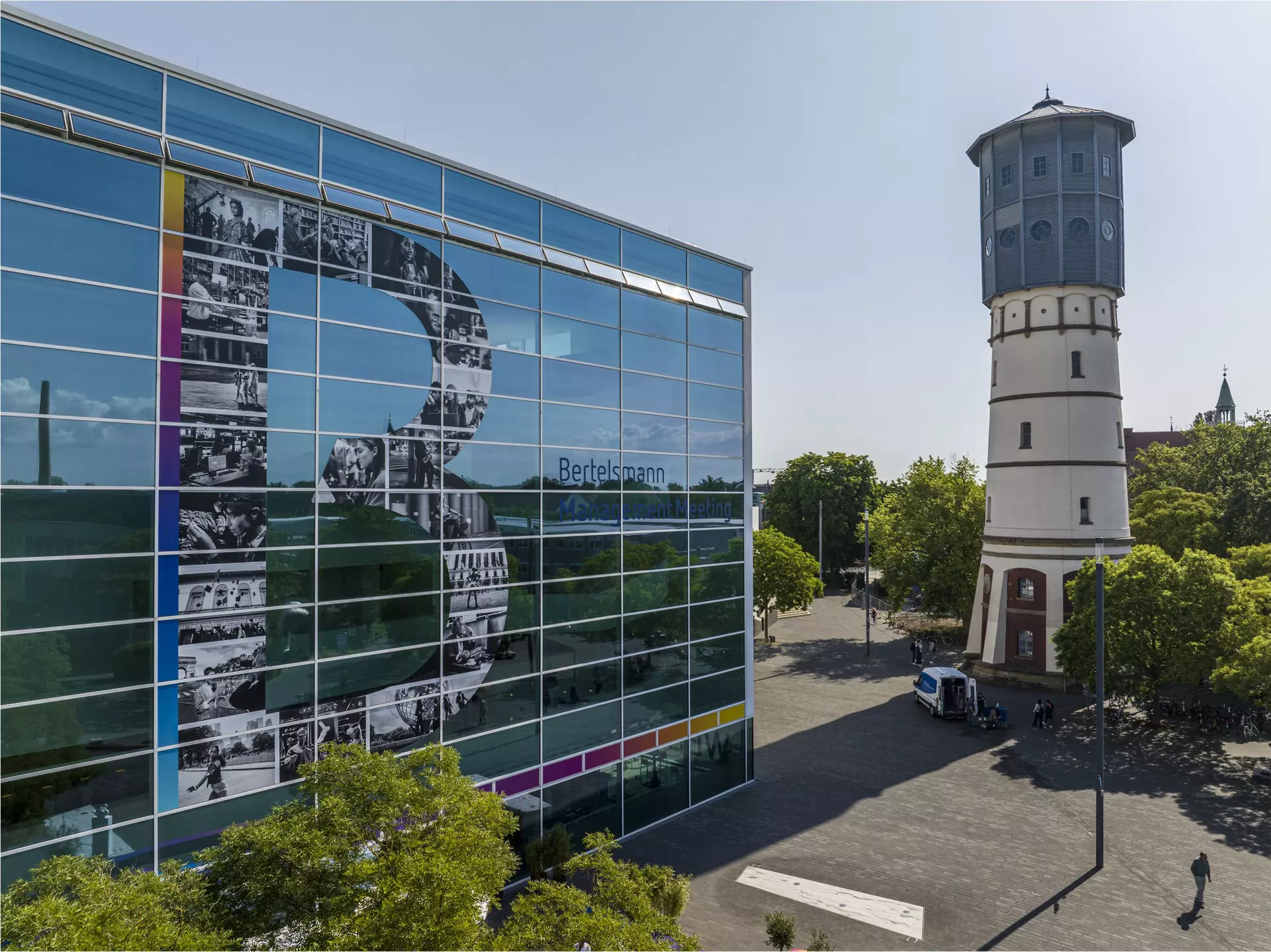 Glasfassade mit großem „B“ neben historischem Wasserturm.