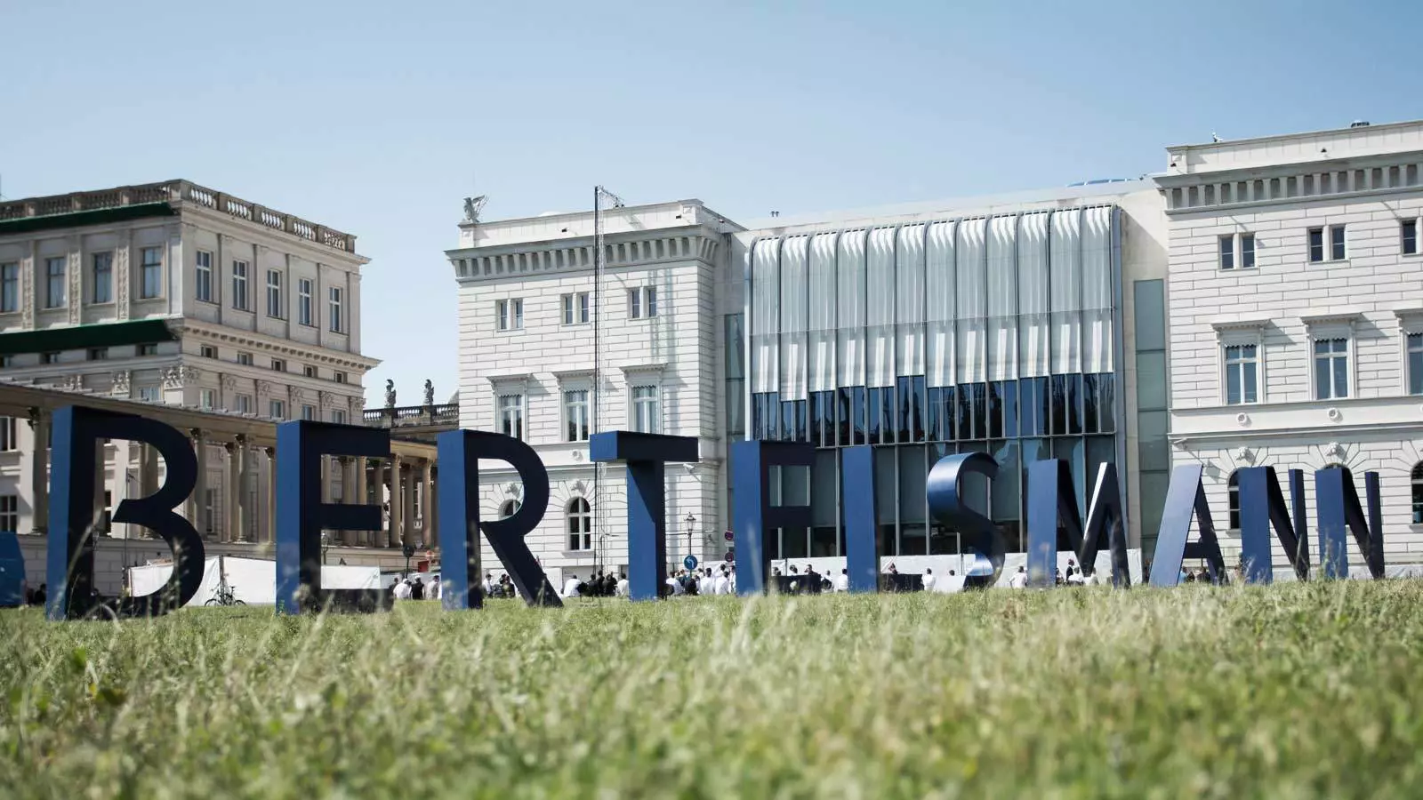 Bertelsmann logo on a green field with a white building behind it