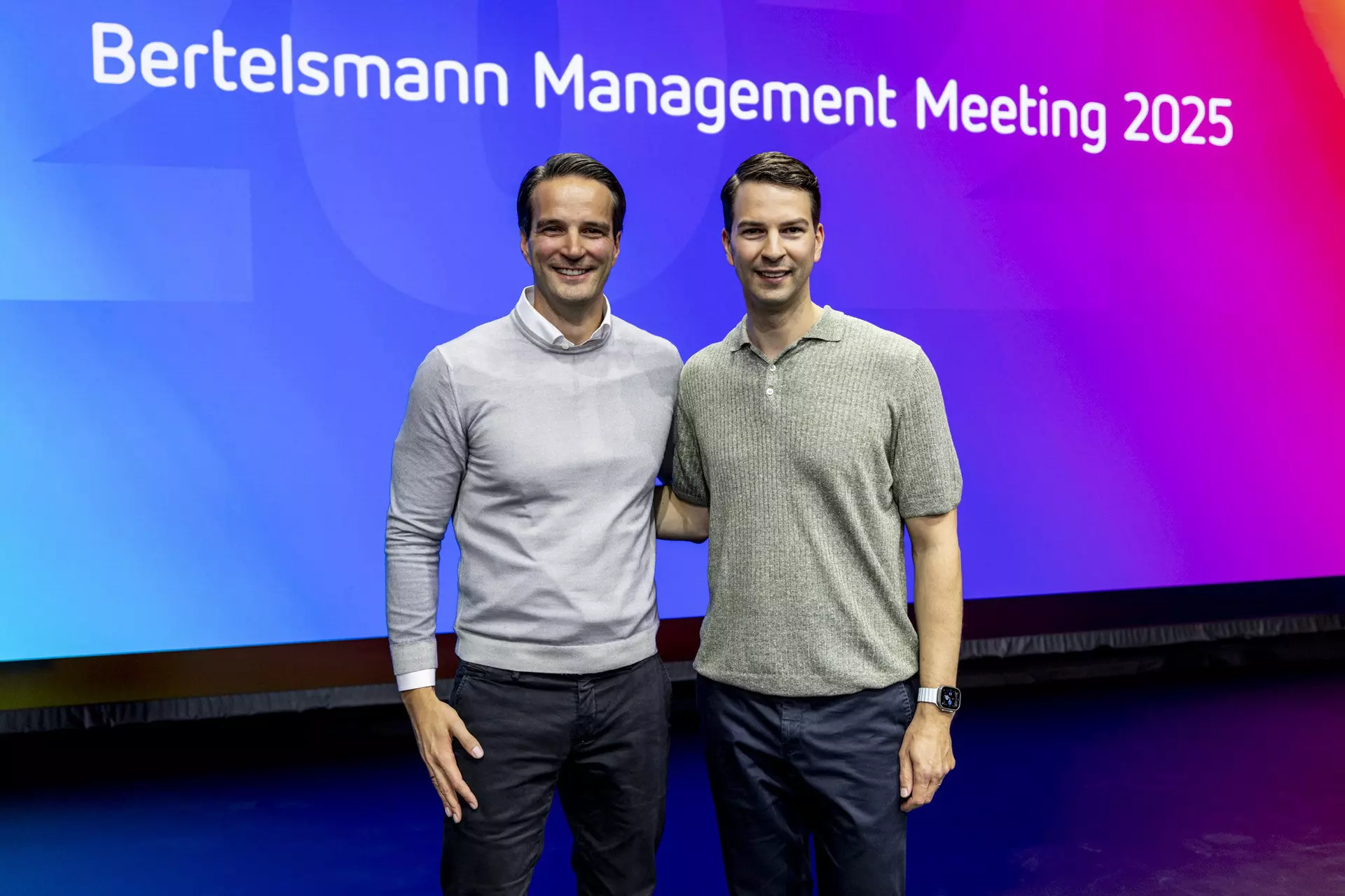 Zwei Personen stehen nebeneinander auf Bühne vor Leinwand mit Schriftzug „Bertelsmann Management Meeting 2025“.