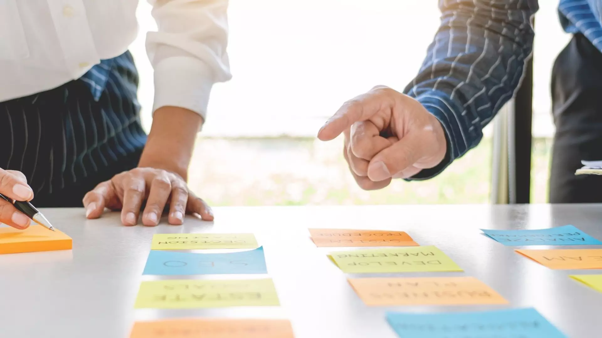 Two people organize colored sticky notes, symbolizing priority setting.