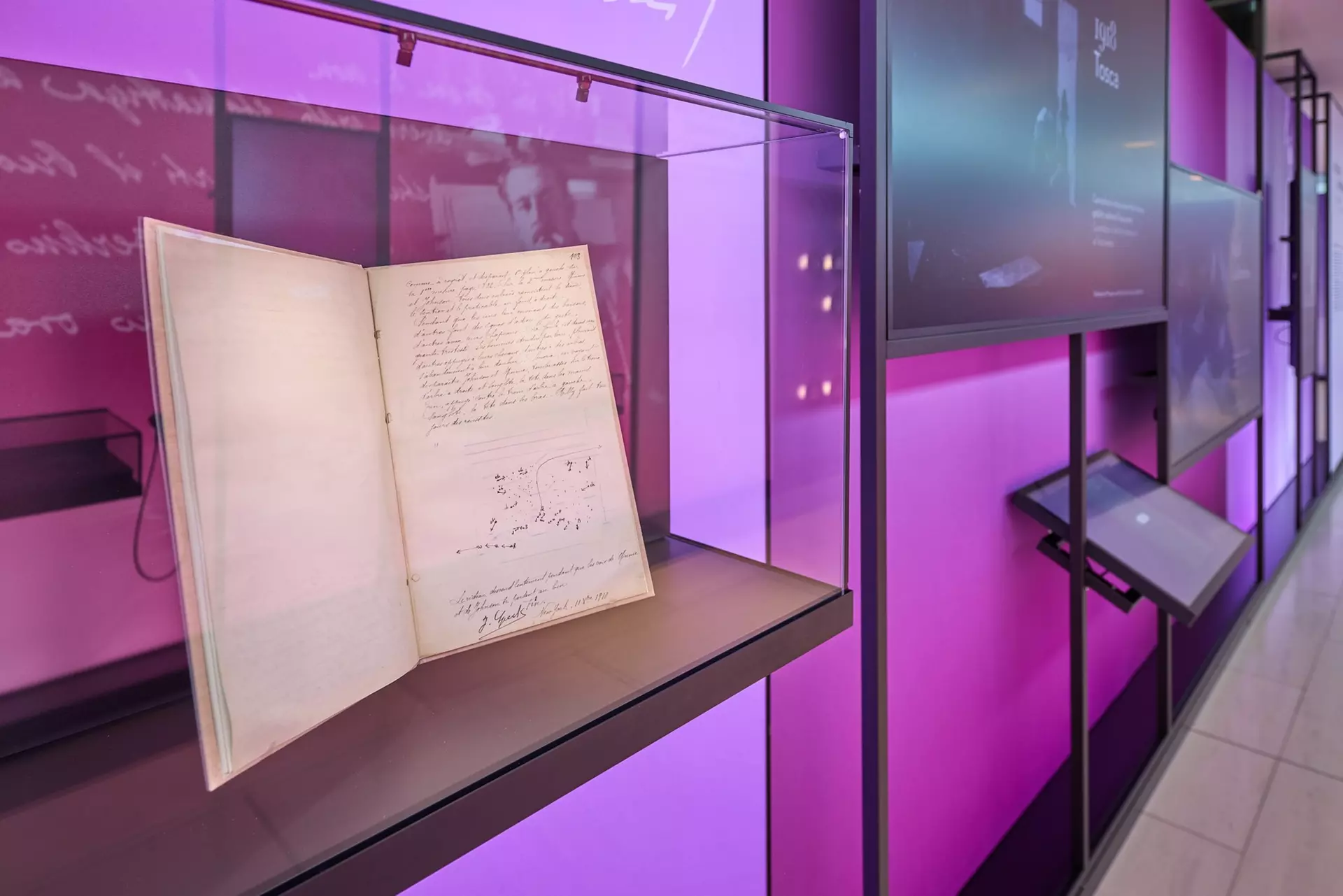 Close-up of an open book containing notes and sketches by Giacomo Puccini, well protected in a glass display case