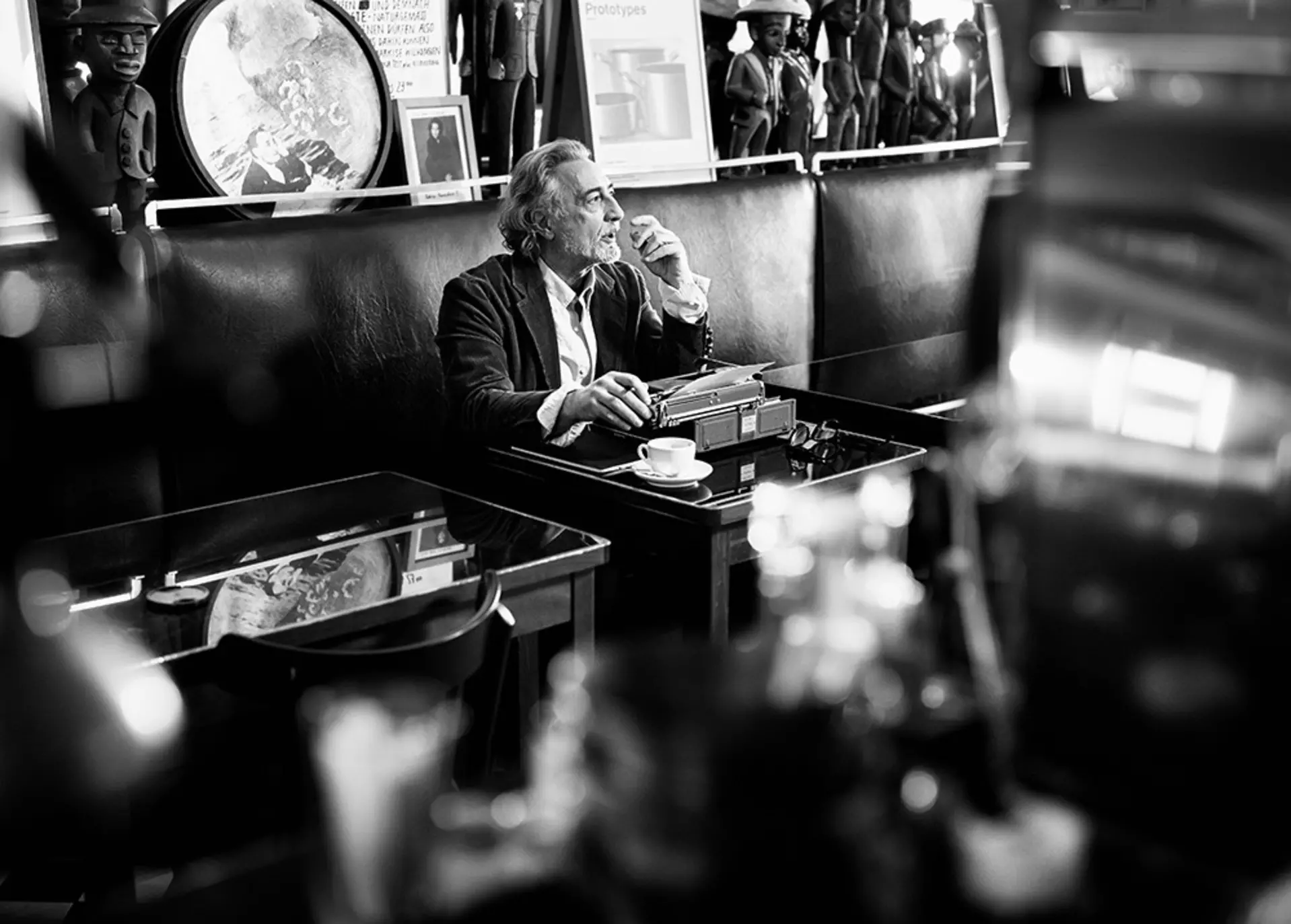 Person sitzt an Schreibmaschine in einem Café mit klassischer Einrichtung.