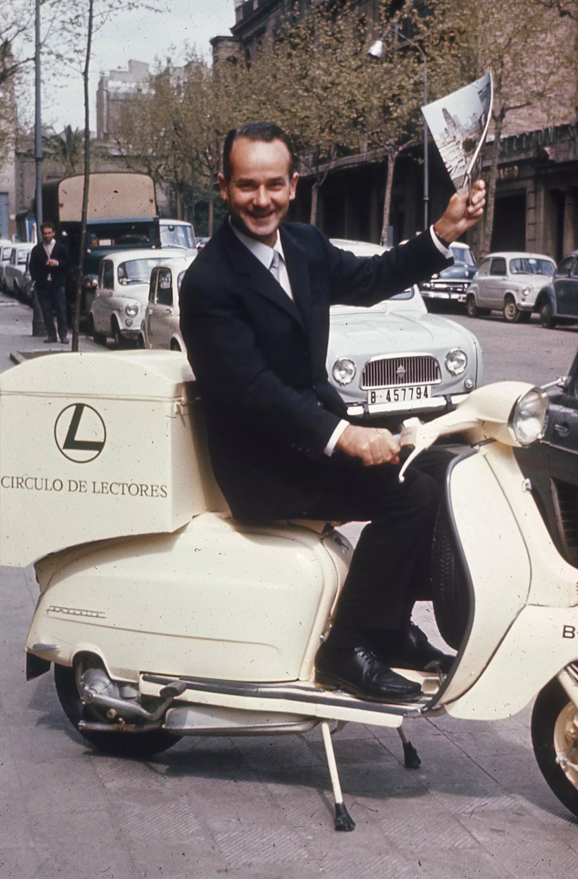 Reinhard Mohn on a motor scooter whose trunk bears the inscription "Circulo des lectores", holding a magazine in his hand