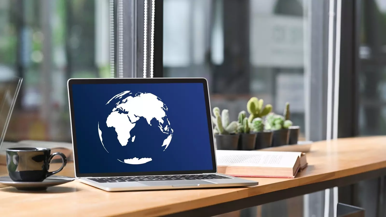 Laptop on desk displays globe icon; represents global cooperation and the UN Global Compact progress report.