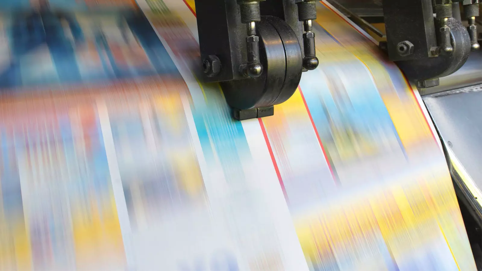 A color print runs through a printing press.