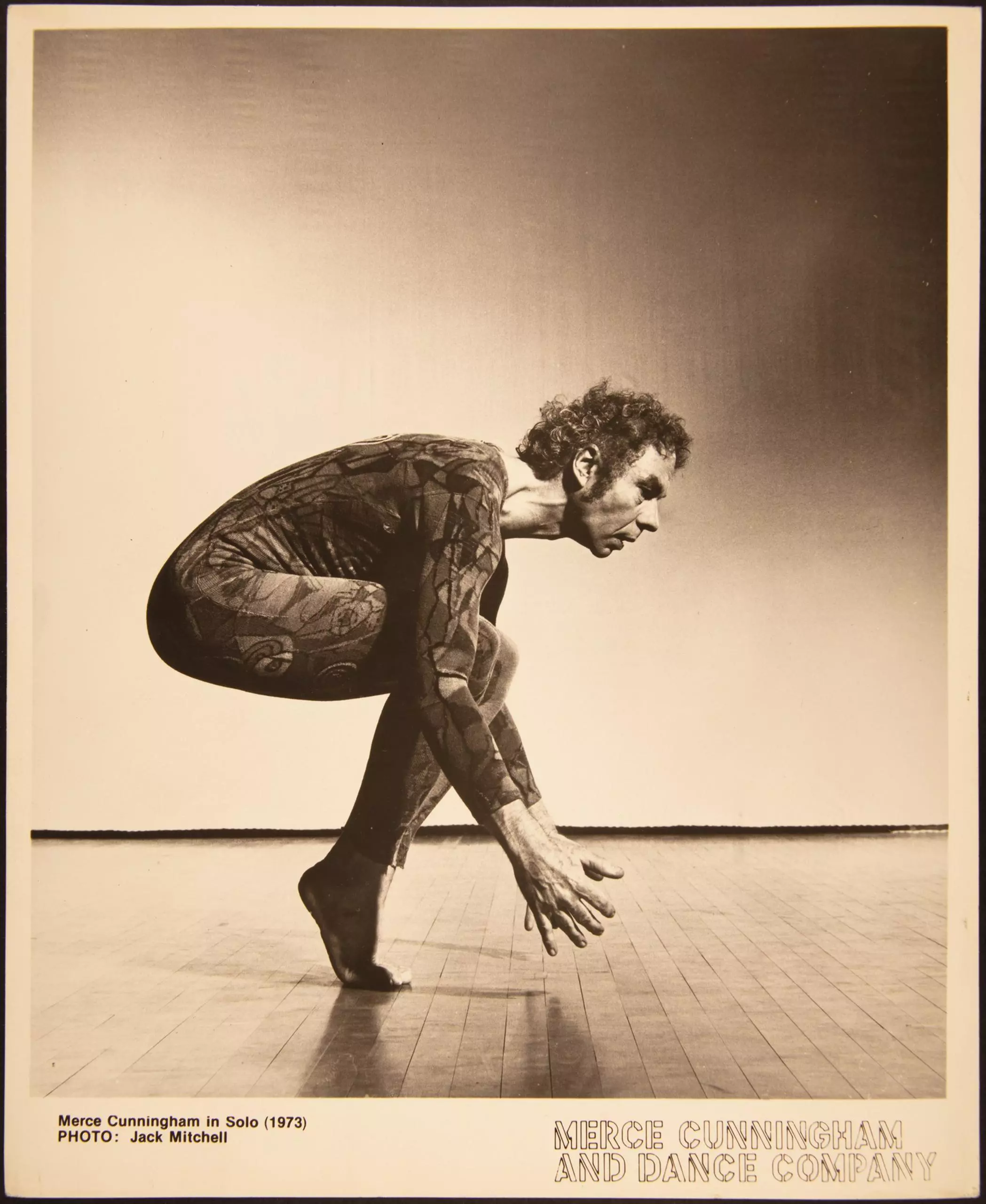 Historisches Foto eines Tänzers in gebeugter Pose auf Bühne, mit Schriftzug „New York City Center“.