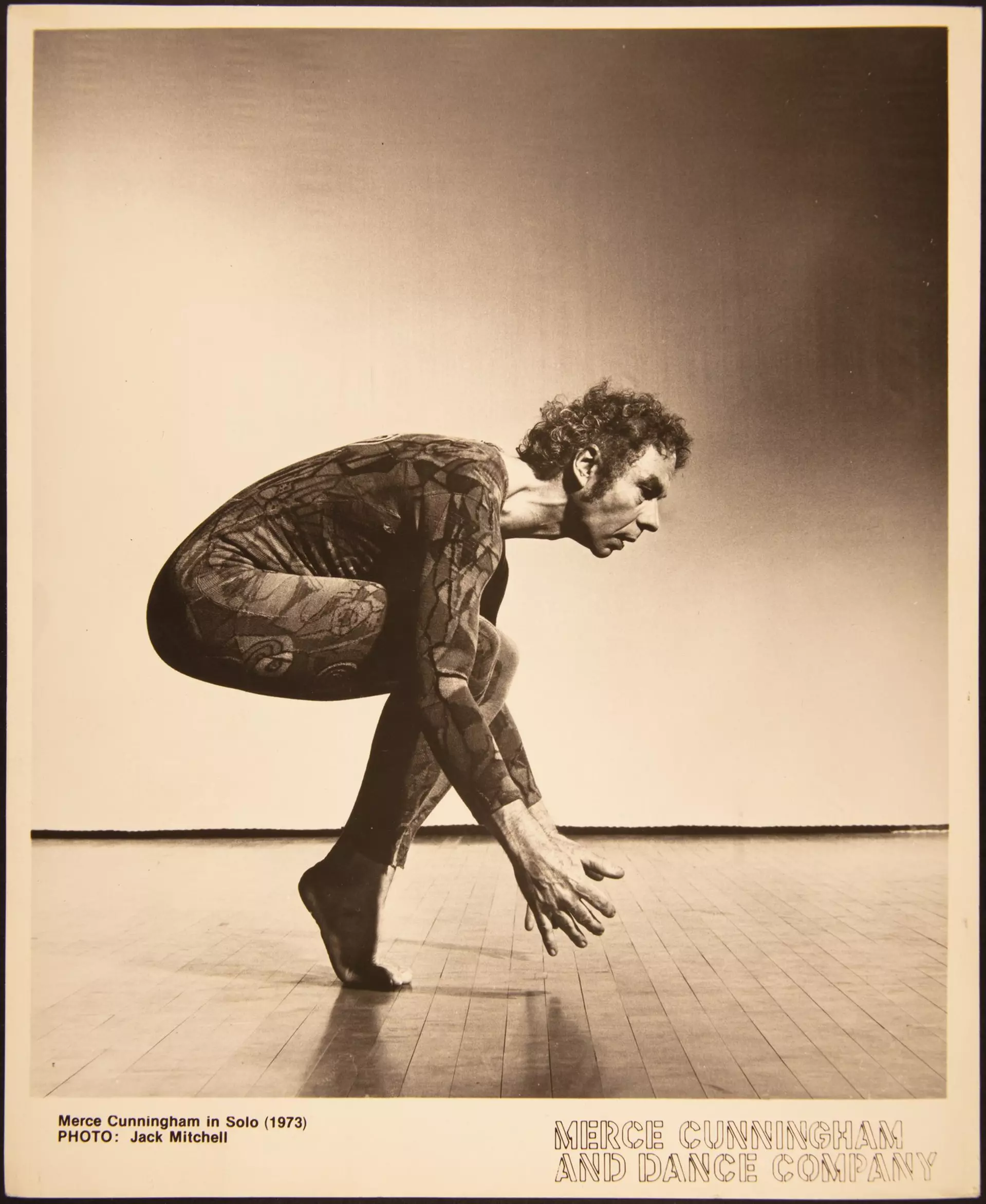 Historisches Foto eines Tänzers in gebeugter Pose auf Bühne, mit Schriftzug „New York City Center“.