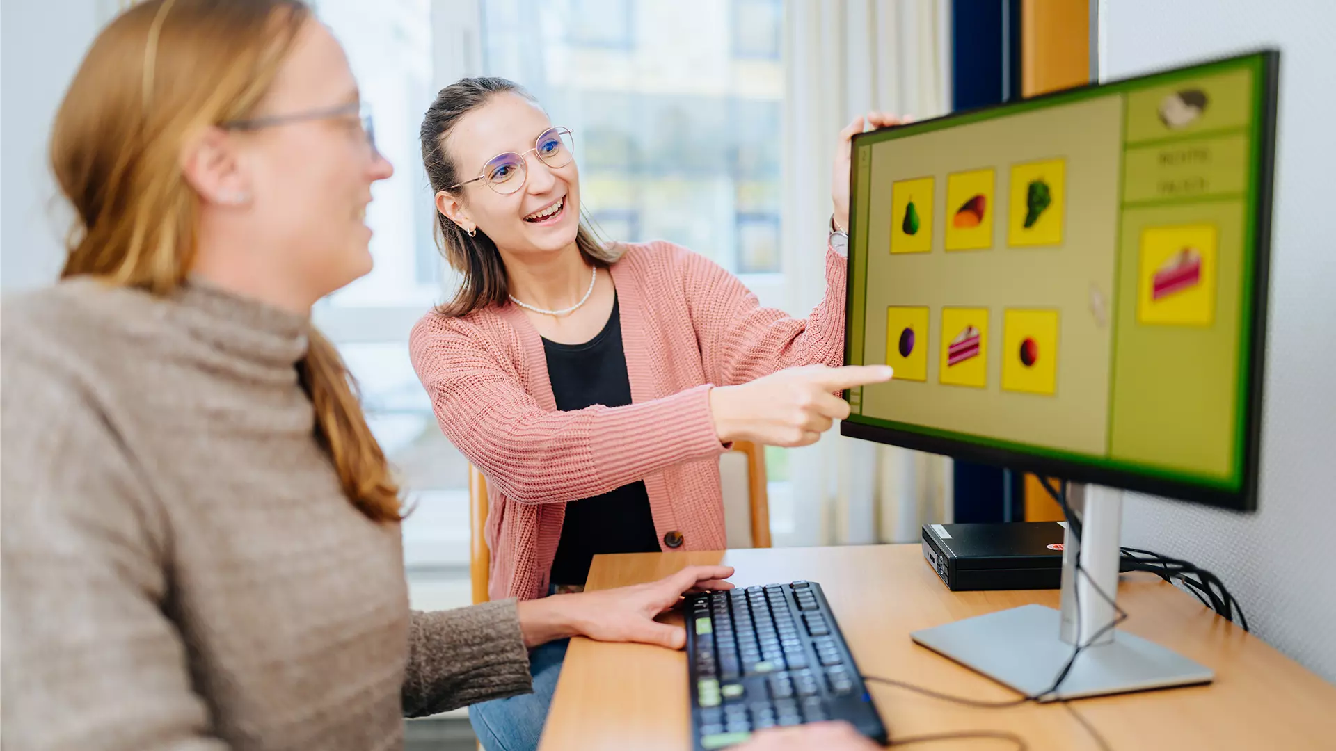 Two women are looking on a screen with symbols